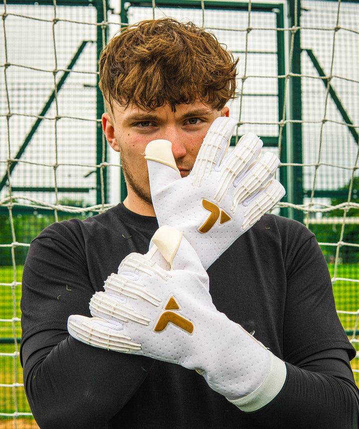 Person wearing black Professional Goalkeeper gloves with a logo, standing in front of a netted background